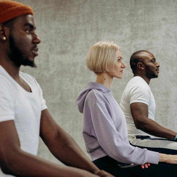 Diverse group of people practicing a simple yoga stretch together.